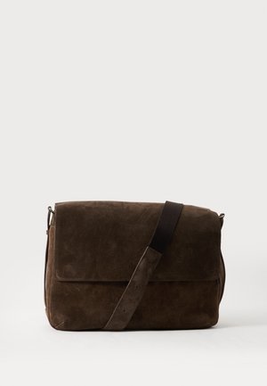 Sac besace en daim marron foncé avec bandoulière ajustable sur fond clair uni.