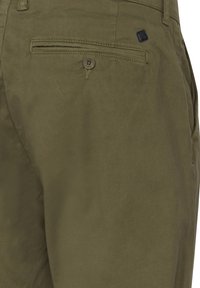 Olivgrüne Hose aus weichem Stoff mit flachem Bund, seitlichen Taschen und einer Gesäßtasche mit Knopfverschluss sowie einer Marken-Tag-Detail.