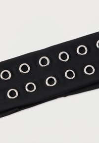 Fekete textilszíj, amely hosszában egyenletesen elhelyezett több ezüstszínű fémszemmel díszített. A felülete sima, enyhén rugalmas anyagból készült.