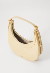 Cream-colored leather handbag with a curved shape, gold hardware, and a zipper closure. Smooth texture and adjustable shoulder strap.