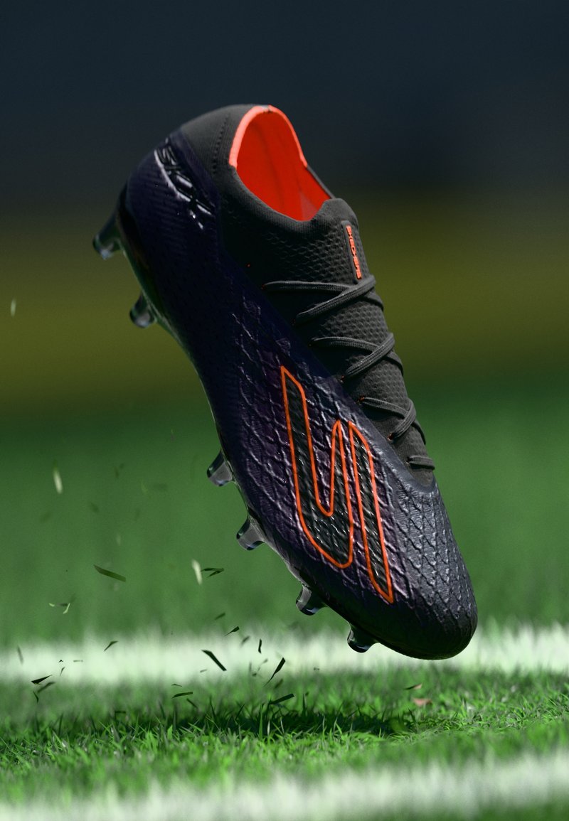 Black soccer cleat with a textured upper, orange accents, and a low-top design. Features multiple cleats on the sole for traction.