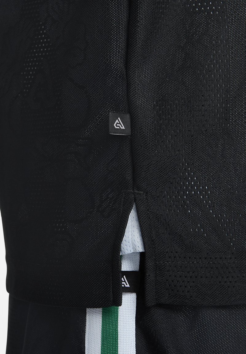 T-shirt de sport noir avec texture en maille. Présente une petite étiquette logo et des fentes sur les côtés ; inclut un motif rayé vert et blanc en dessous.