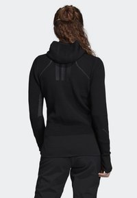 Hoodie en maille noire avec un design texturé, une coupe ajustée et une capuche à col montant. Comprend des empiècements contrastants et des poignets avec trous pour les pouces.