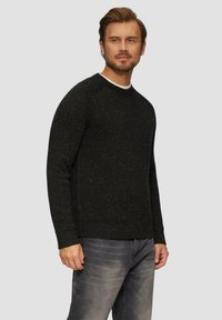 Schwarzer Strickpullover mit gesprenkelten Akzenten, ausgestattet mit einem Rundhalsausschnitt und gerippten Bündchen, kombiniert mit grauen Jeans.
