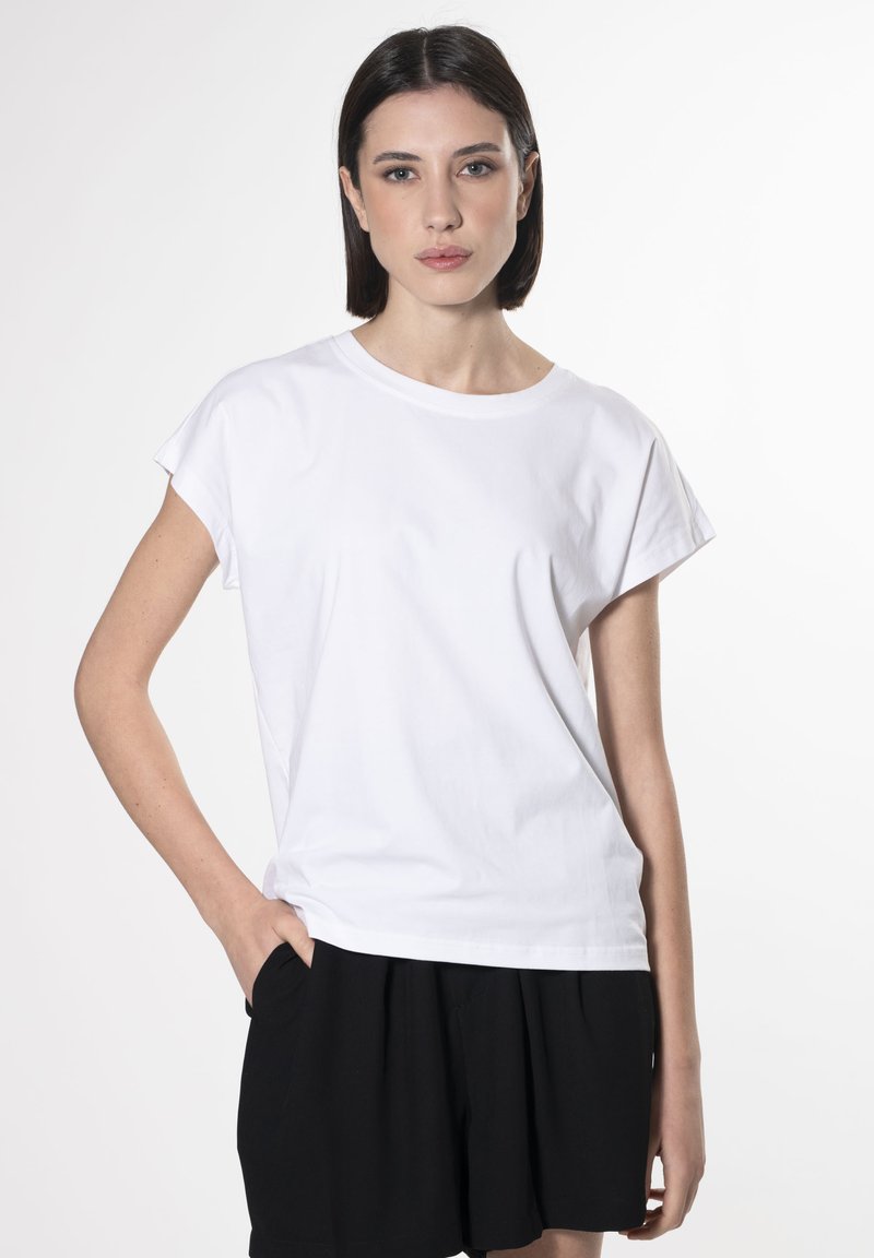 T-shirt bianco a maniche corte con scollo tondo, realizzato in tessuto di cotone. Abbinato a pantaloni corti neri, caratterizzati da una vestibilità comoda e una texture liscia.