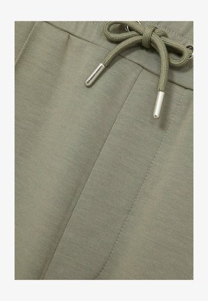 Heledad oliivrohelised dressipüksid pehmest kangast, millel on paelaga sulgemine metalltipudega ja külgedel õmmeldud detailid.