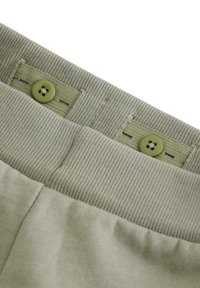 Grøn bomulds taljebånd med to knapper, struktureret ribstrik øverst og glat stof nedenunder. Har et diskret tone-i-tone design.