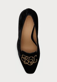 Čierne zamatové slip-on topánky s špicatou špičkou, s vyšívaným zlatým detailom vpredu a hladkým hnedým interiérom.