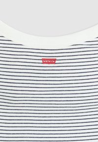 Prugasta pamučna majica s tankim tamnoplavim prugama na bijeloj podlozi, s crvenom oznakom Levi's na vratu.