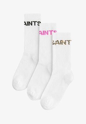 Három pár fehér zokni bordázott textúrával; az egyik pár fekete felirattal rendelkezik, a másik rózsaszín, a harmadik pedig leopárd mintás.