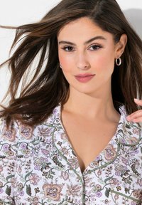 Květinový pajama top v bílé barvě, s fialovými a zelenými akcenty, s klopovým límcem a krátkými rukávy. Hladká textilie.