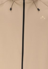 Veste beige avec fermeture éclair centrale noire, cordons de capuche réglables avec embouts noirs, et petit logo géométrique sur la poitrine.