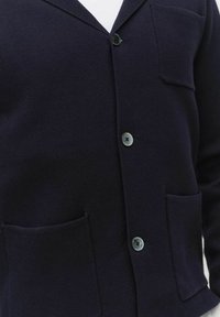Donkerblauwe cardigan van gestructureerde brei stof, met een sjaalkraag, twee voorzakken en drie knopen.