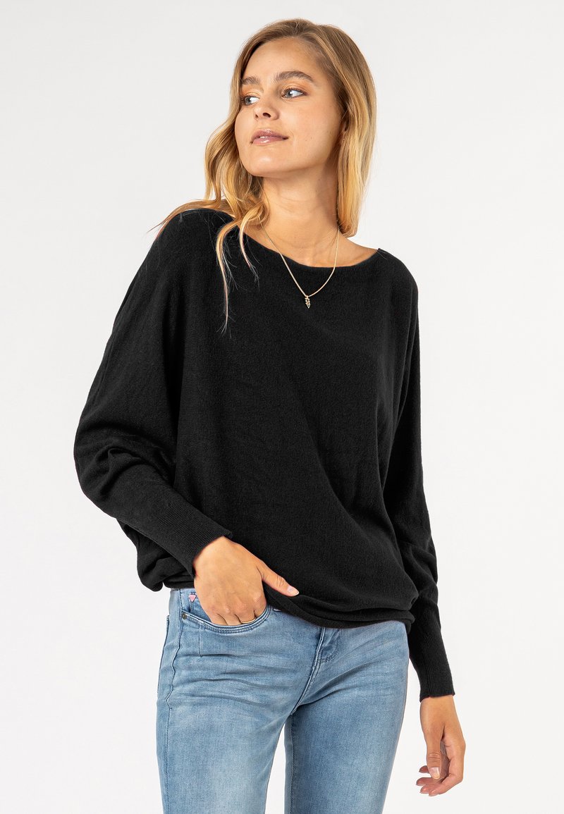 Black, long-sleeve sweater in a relaxed fit with a wide neckline. Soft texture, paired with light blue jeans, reveals casual styling.