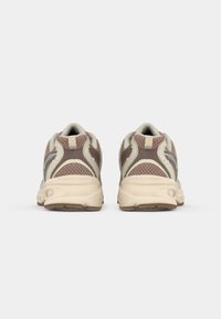 Footwear featuring a beige and brown mesh upper, padded collar, and a cushioned cream sole. Design emphasizes breathability and support.