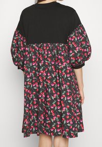 Czarna sukienka krótko rękawowa w kwiatowy wzór czerwonych i różowych wiśni, z marszczoną talią i teksturowanymi bufkami.