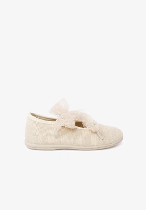 Scarpa piatta beige con suola morbida e grande fiocco decorativo in rete sulla parte superiore, vista dal lato esterno.