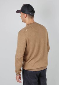 Pull marron à manches longues, avec des bords côtelés au niveau des poignets et de l'ourlet, en tissu texturé, présentant un petit logo sur l'épaule.