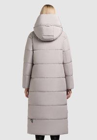 Cappotto piumino lungo grigio chiaro con cappuccio, caratterizzato da sezioni trapuntate, maniche lunghe e un'etichetta con logo sul lato sinistro vicino all'orlo.