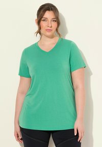 Zelené tričko s krátkým rukávem ve tvaru V, vyrobené z měkké, hladké látky s volným střihem. Bez viditelných vzorů nebo akcentů.
