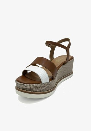 Sandalo con zeppa marrone e bianco, con cinturino alla caviglia e suola platform texturizzata, progettato per un uso estivo elegante.