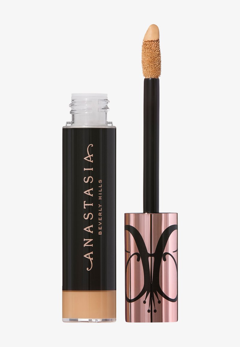 Liquid concealer in a clear tube with a black cap, featuring a soft applicator tip. The packaging has gold and black lettering.