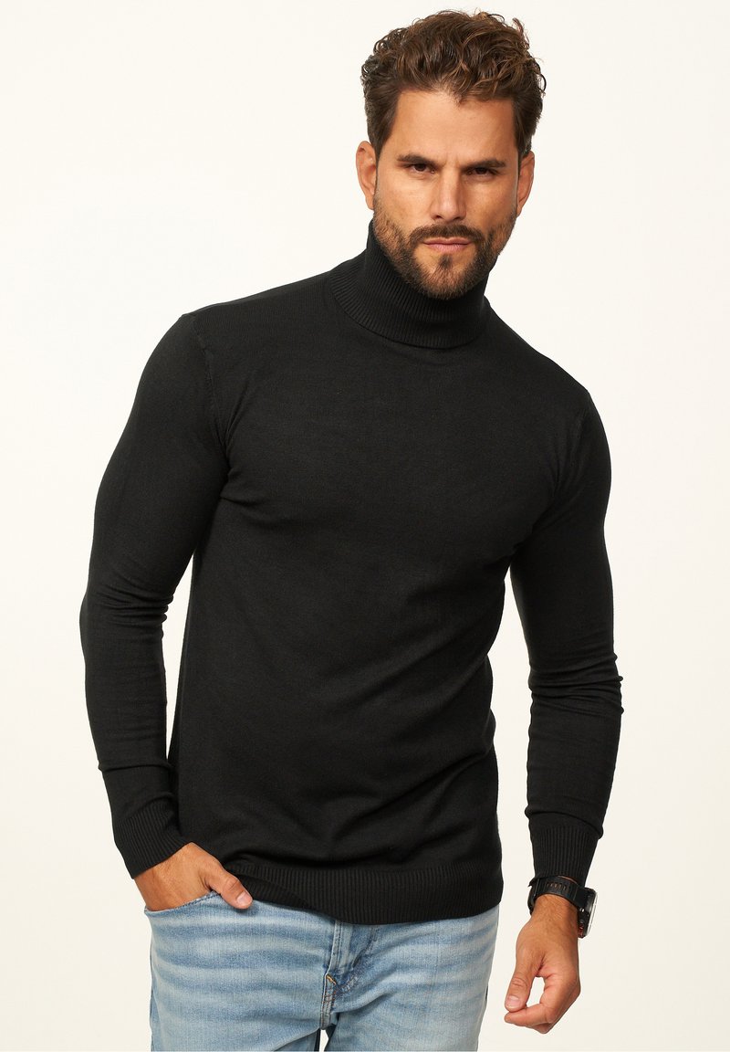 Black turtleneck sweater made of smooth fabric with long sleeves, ribbed cuffs, and waistband, paired with light blue jeans.