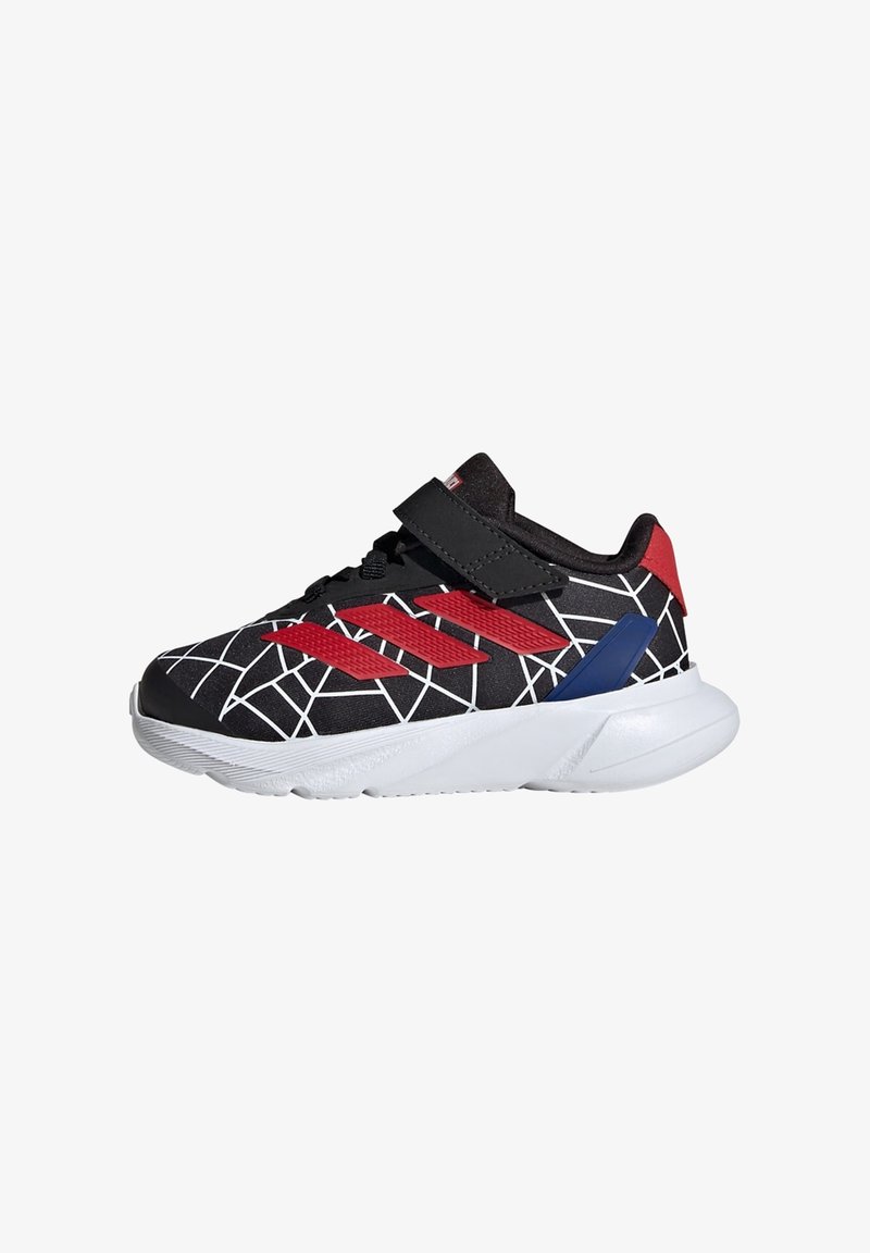 Chaussure de sport noire avec des accents rouges et bleus ; présente un motif en toile, une sangle Velcro et une semelle blanche texturée.