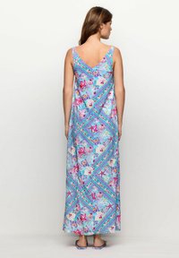 Maxime dress in a floral pattern featuring shades of blue, pink, and green. Sleeveless design with a V-back and flowing silhouette.