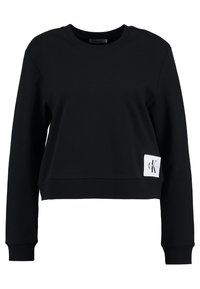 Czarna krótka bluza z długim rękawem, okrągłym dekoltem i małą białą naszywką z logo Calvin Klein po lewej stronie u dołu.