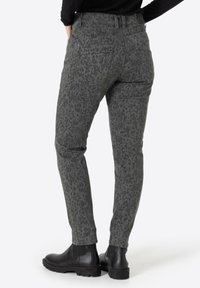 Gray patterned trousers featuring a subtle leopard print, slim fit design, five pockets, and worn with black ankle boots.