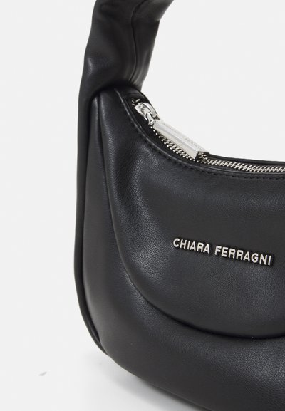 Melnas ādas plecu soma ar izliekta dizainu, sudraba rāvējslēdzis un uz priekšpuses iedzīta zīmola nosaukums. Mīksta tekstūra, elegants izskats.