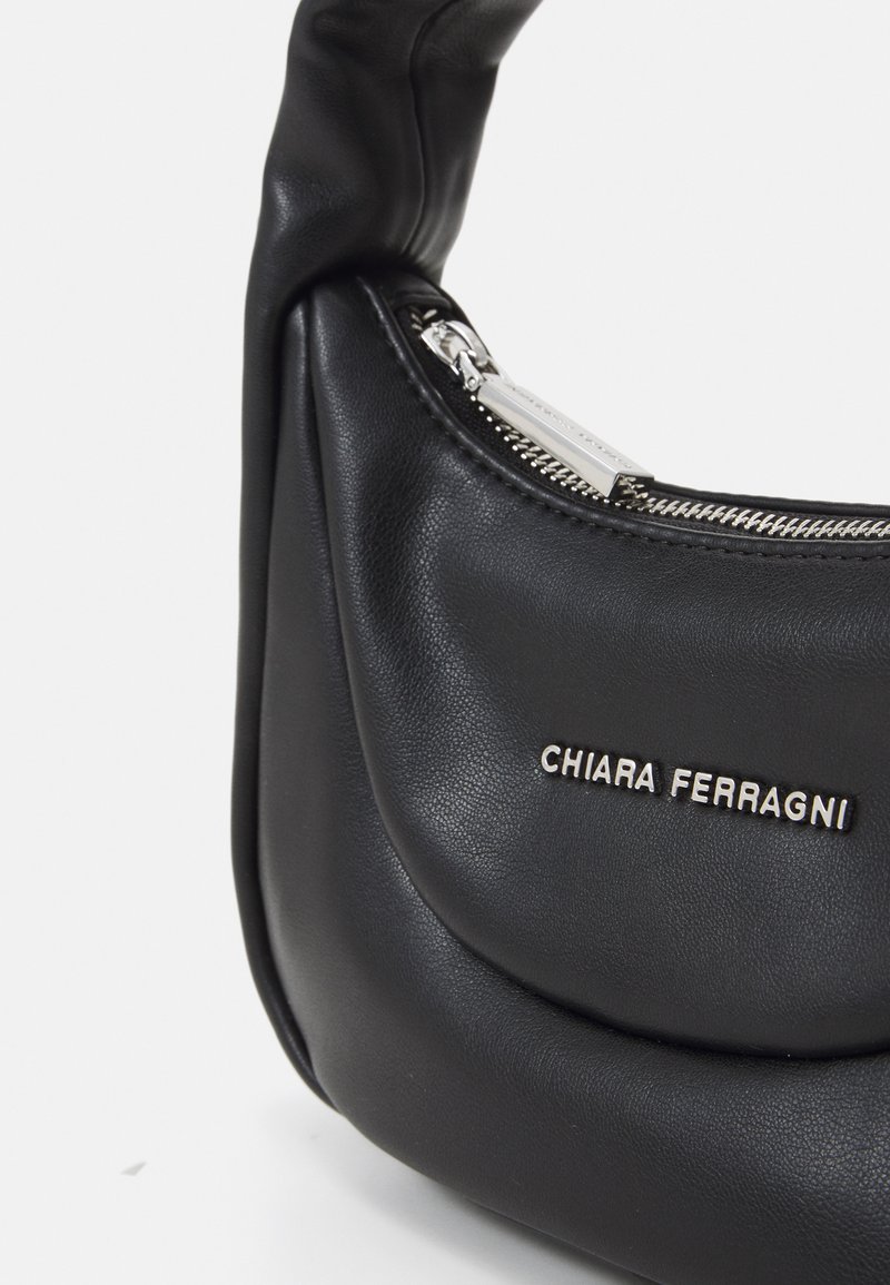 Borsa a spalla in pelle nera con design curvo, cerniera argentata e nome del marchio in rilievo sulla parte anteriore. Tessuto morbido, aspetto elegante.