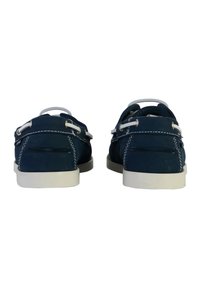 Chaussures en daim bleu marine avec des coutures blanches et un talon rehaussé, dotées d'un matériel métallique et d'un design décontracté équilibré.