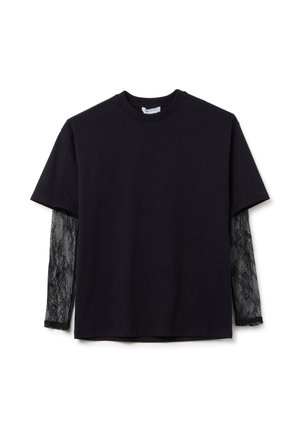 T-shirt negra de manga corta, con mangas largas de encaje transparente. El encaje tiene un patrón floral, creando un contraste de textura en capas.