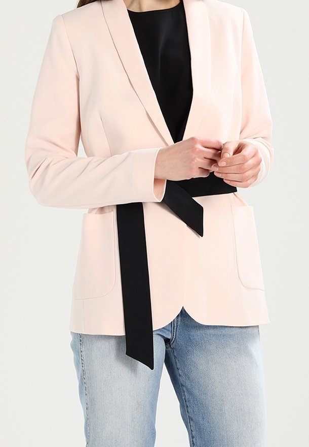 Jasnoróżowa marynarka z miękkiej tkaniny, z kołnierzem z klapami, przewiązana czarnym paskiem w talii, z dwoma przednimi kieszeniami i luźnym krojem.