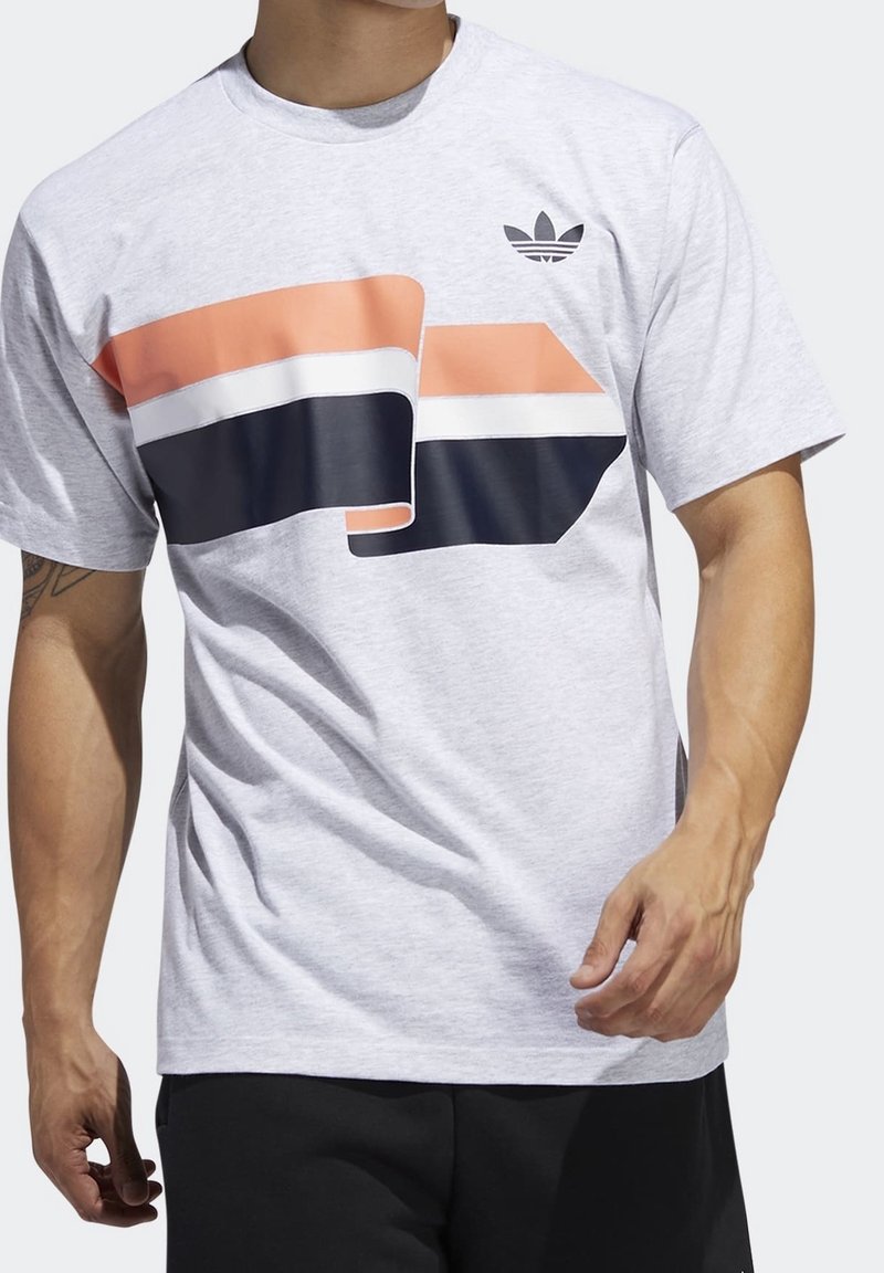 Světle šedé bavlněné tričko s velkým potiskem s oranžovými, černými a bílými pruhy. Malé černé logo v horním levém rohu.