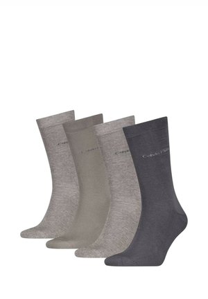 Quattro paia di calzini Calvin Klein a metà polpaccio in diverse tonalità di grigio, disposti affiancati, con un logo sottile vicino al bordo superiore.