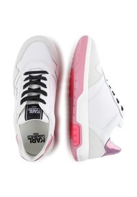Λευκό αθλητικό παπούτσι από δέρμα και σουέτ, με μαύρες κορδόνες, ροζ ελαστική σόλα και γυαλιστερή ροζ λεπτομέρεια στη φτέρνα.