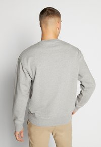 Grå sweatshirt med rund hals, långa ärmar och ribbade muddar. Mjukt tyg med avslappnad passform, utan synliga logotyper eller mönster.