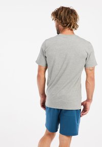 Grijs t-shirt met korte mouwen en ronde hals, gemaakt van een katoenmix, gedragen met blauwe sportshorts met een zijzak.