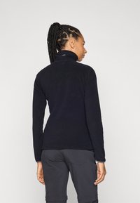 Pullover in pile nero con colletto alto e maniche lunghe, caratterizzato da un logo discreto sul retro e da una superficie liscia e morbida.