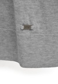 Pull gris avec une texture lisse et un ourlet côtelé. Présente une petite étiquette de marque étiquetée "POLO CLUB" près du bas.