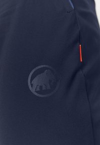 Donkerblauwe sportbroekjes van gladde stof, met een tonale olifantenlogo en een oranje accentlabel voor detail.