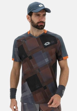 Camiseta atlética de manga corta con un patrón geométrico en tonos oscuros, con acentos naranjas y un escote en V. Complementada con una gorra a juego.