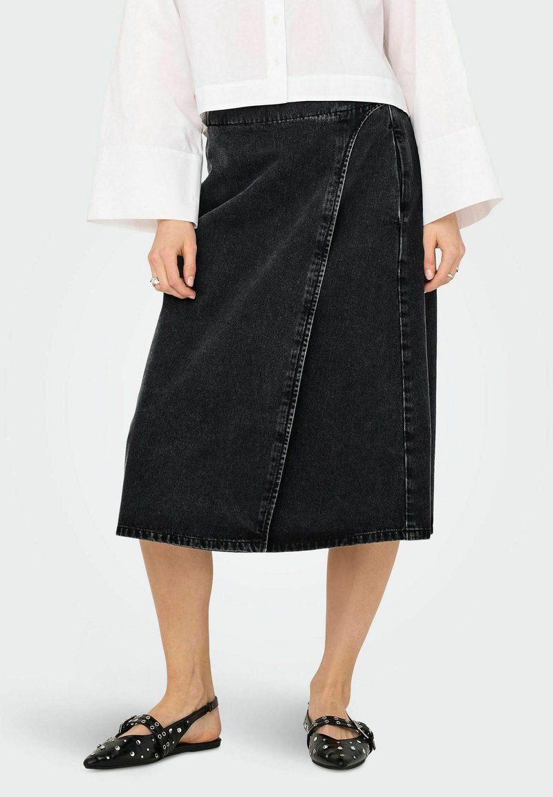 Svart denimkjol i knälängd med knytning i sidan, med en sidoseamsdetalj och en subtil textur. Bärs med svarta flatskor med nitar.