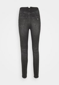 Jeans de mezclilla negra ajustados con una cintura de altura media, dos bolsillos traseros y cierre de cremallera. La tela tiene un ligero estiramiento y una textura suave.