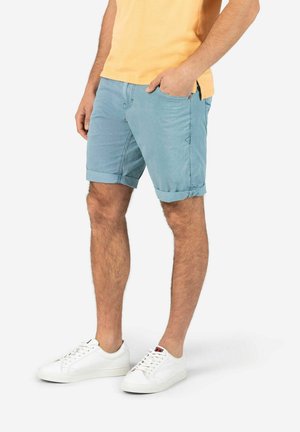 Hellblaue gestreifte Shorts aus Baumwollmischung, mit umgekrempelten Säumen, seitlichen Taschen und einer lockeren Passform, kombiniert mit weißen Sneakers.