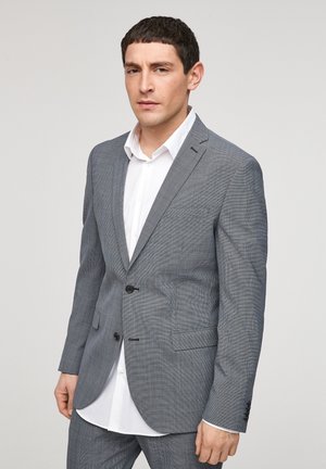 Grijs geruit pak met een notch revers, een twee-knopen voorkant en voorste klepzakken, gedragen over een wit shirt. Gladde textuur.