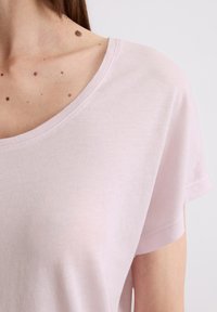 Lichtroze, top met korte mouwen en een wijde halslijn, gemaakt van zachte stof, met een gladde textuur en minimale naden.